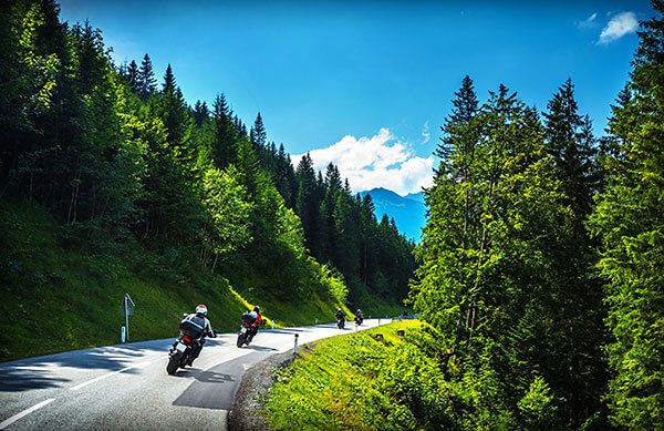 A group of motorcyclists travelling up a scenic mountain road