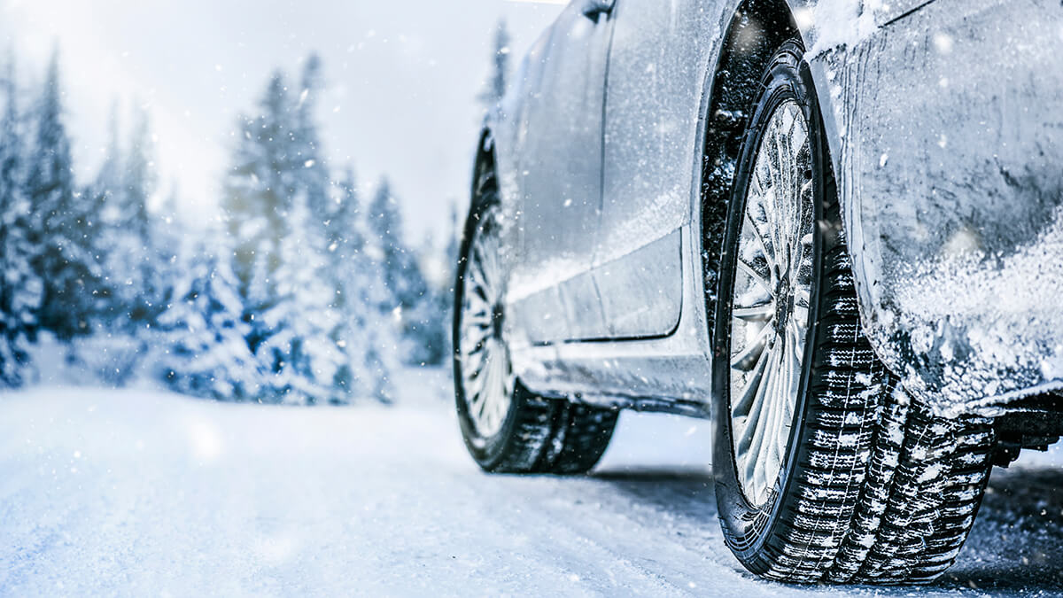 A close-up of a snow tire on a snowy road.