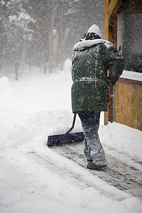 A man shoveling a walkway.