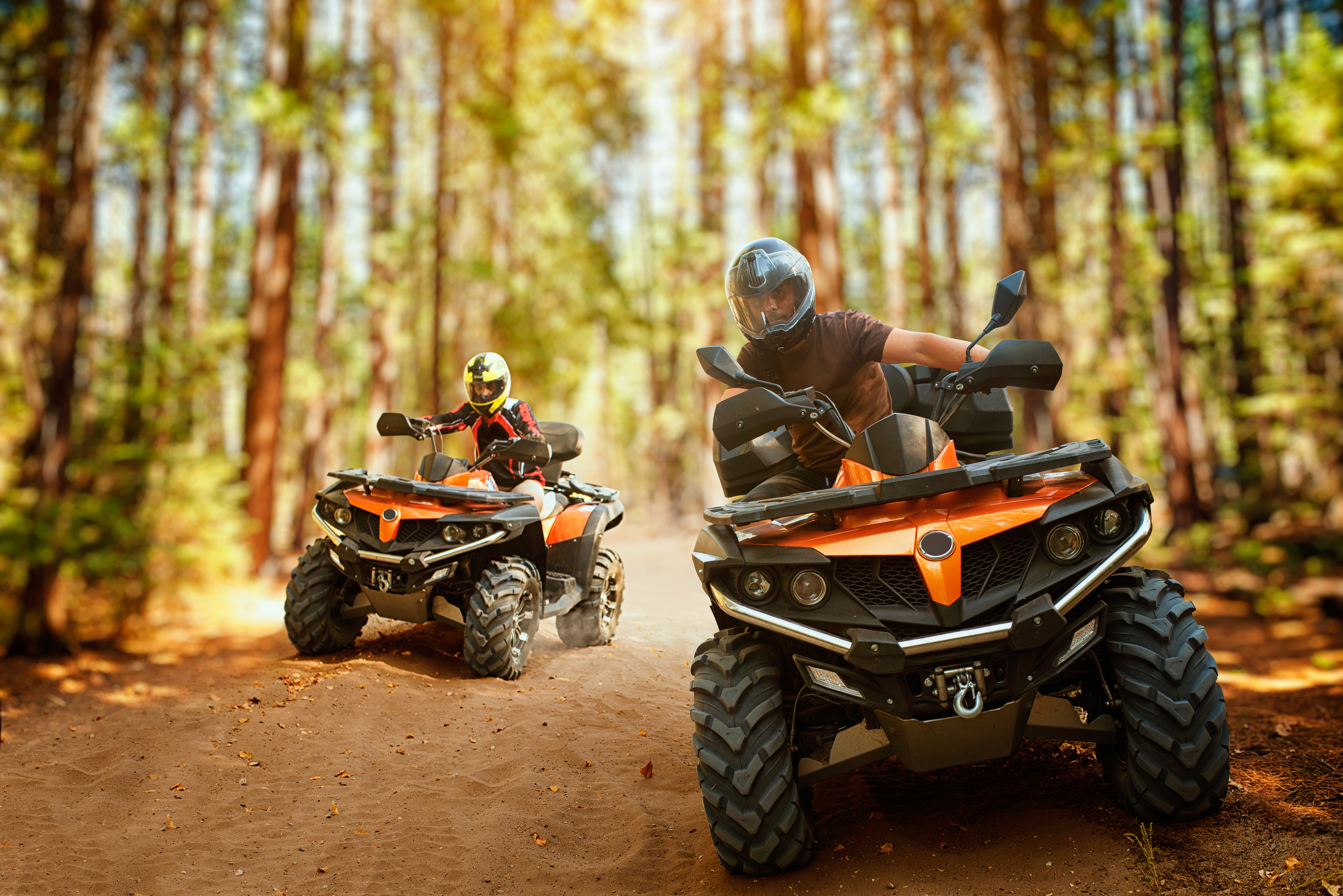 Two ATV's riding a trail in the woods