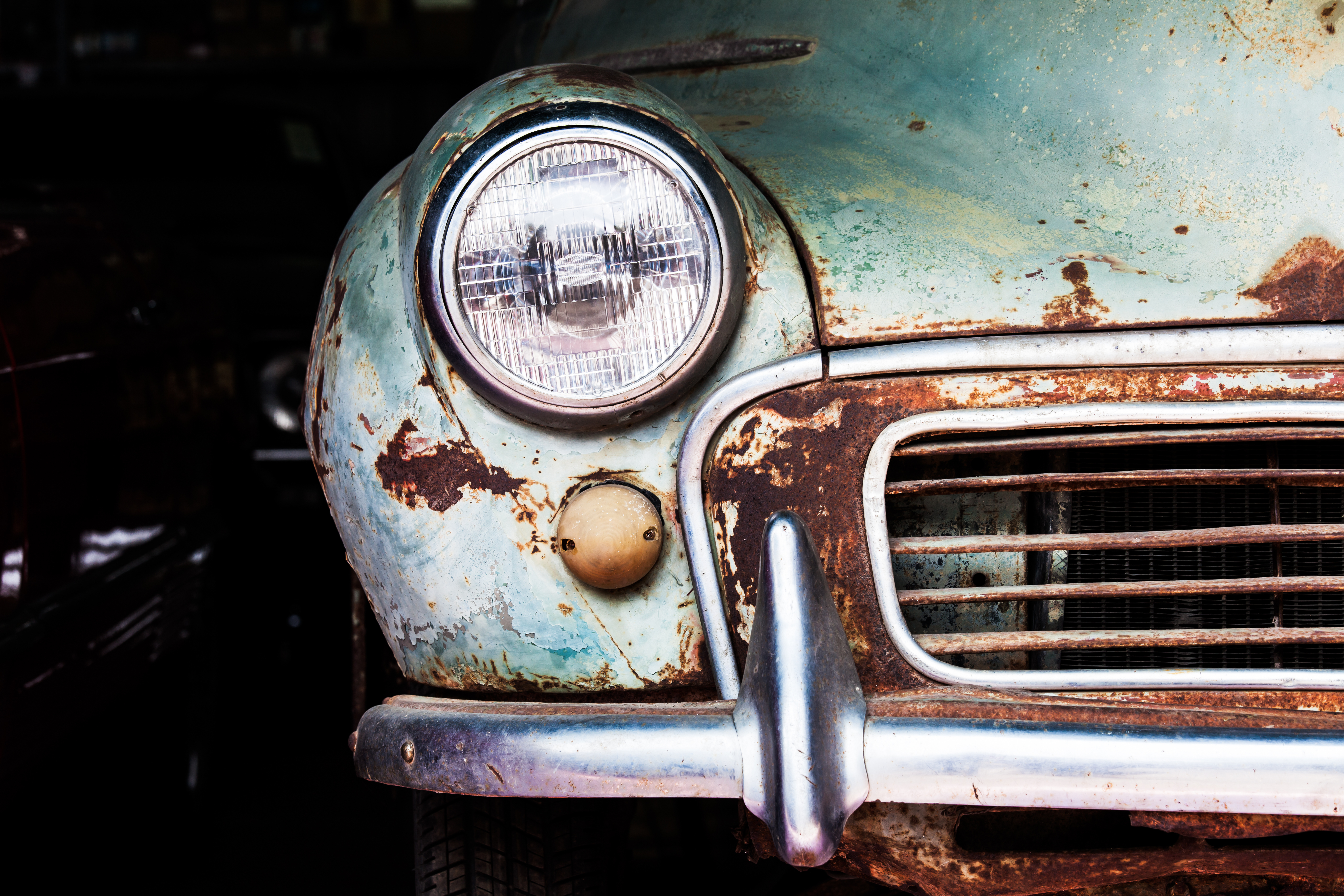 A rusty classic car, with a faded light blue paint job.