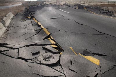 A damaged road with areas of buckling