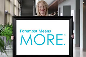 A woman holding a sign saying, 'Foremost Means MORE.'