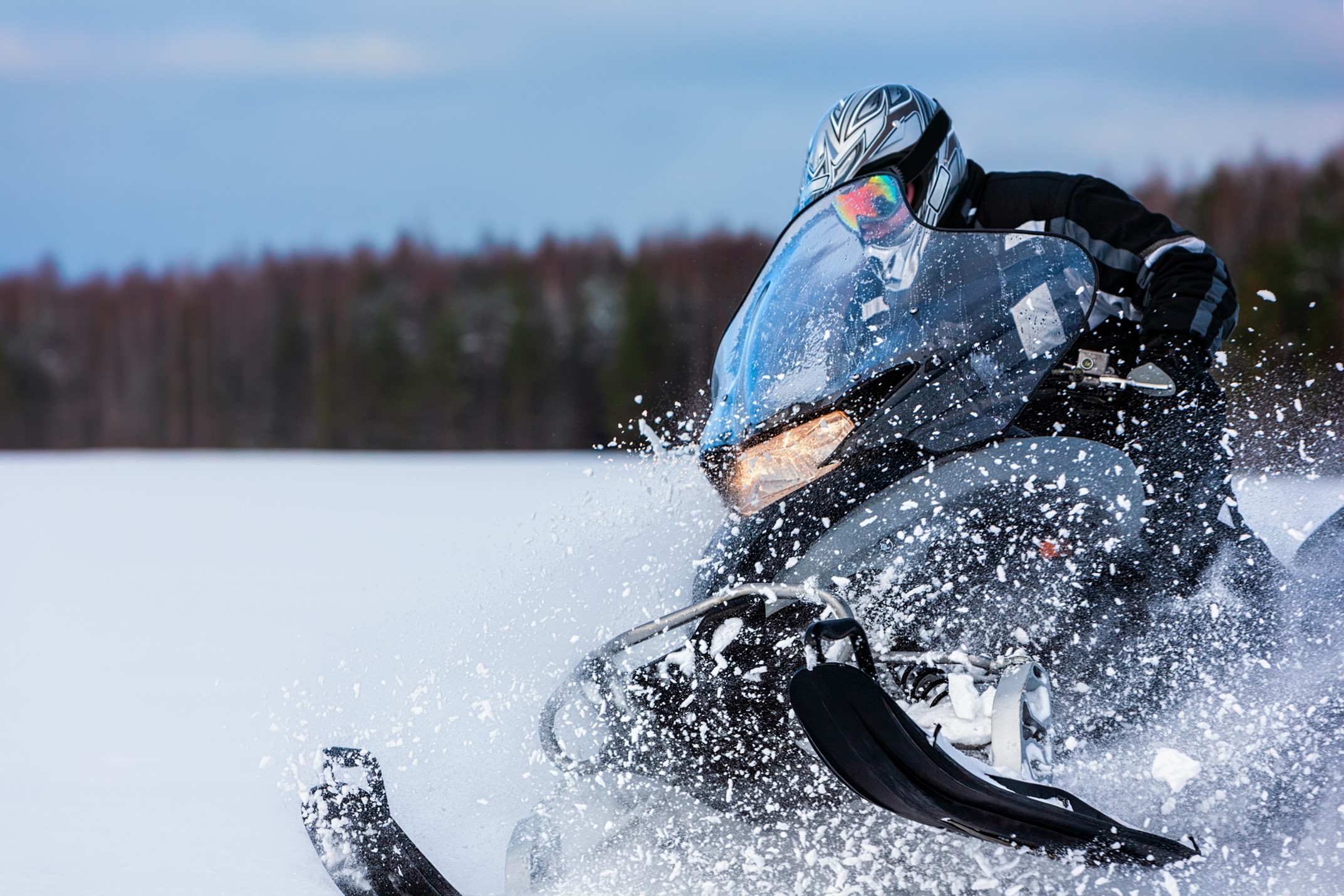 Snowmobilers in a turn with snow kicking up