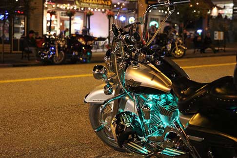 Beautiful motorcycle parked on street with street lights and businesses in background