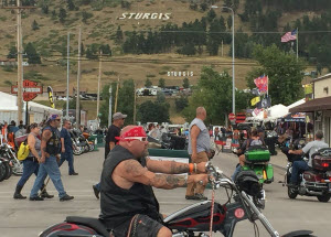 Man with red bandana on motorcycle with black hills in background