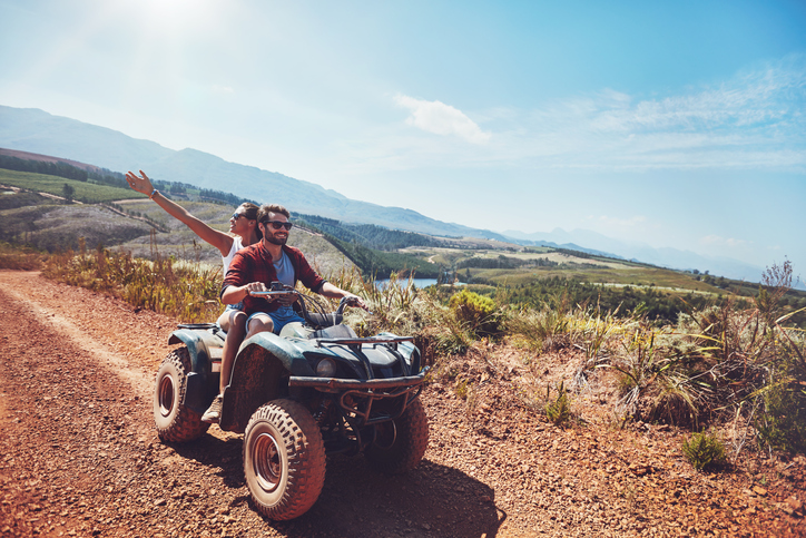 An ATV rider riding a mountain trail in the sunshine