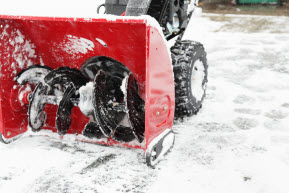 Red snowblower clearing snow on driveway