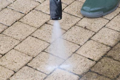 A brick sidewalk being cleaned by a pressure washer